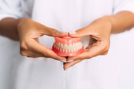 Lady presents viewer with dentures