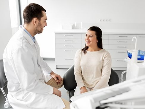 Smiling patient talking with her dentist